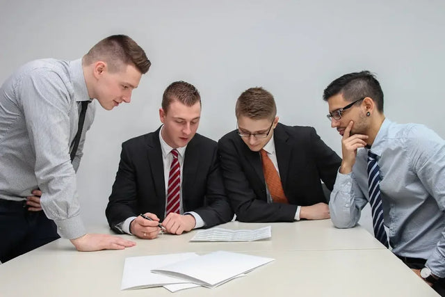 Four businessmen in suits fostering employee empowerment at a table