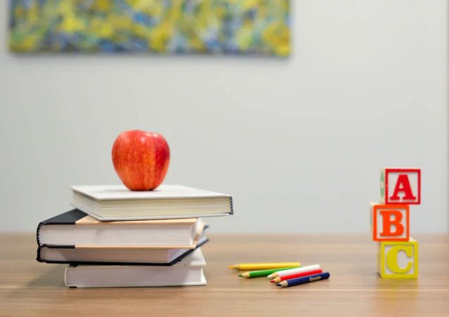 Stack of books with red apple symbolizing visionary leadership in teacher retention