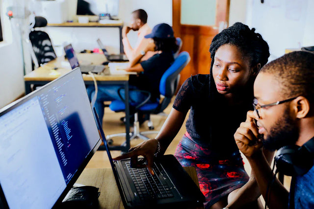 Coworkers collaborating on computer code, enhancing trust among team members.