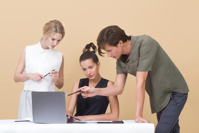 Three people collaborating around a laptop to encourage innovative practices and boost creativity at Avodah Dynamics
