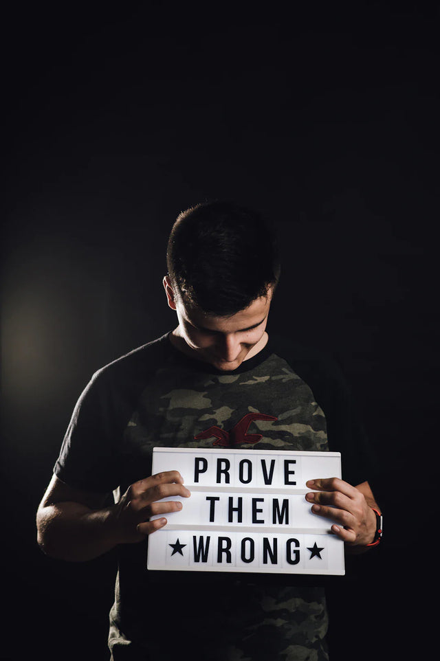Young man in camouflage t-shirt holding illuminated message board with positive affirmations for building confidence in hustle culture
