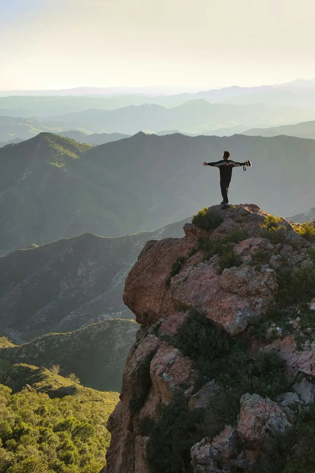 Silhouetted figure on cliff edge symbolizes building resilience and embracing hustle culture.
