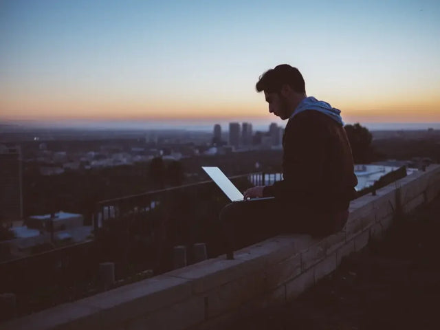 Silhouetted person using a laptop at dusk, symbolizing remote leadership and building trust.