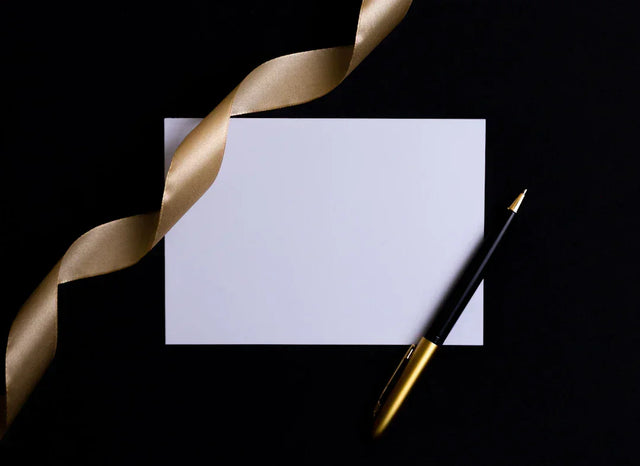Blank white paper with gold ribbon and pen symbolizing celebrating success stories in education