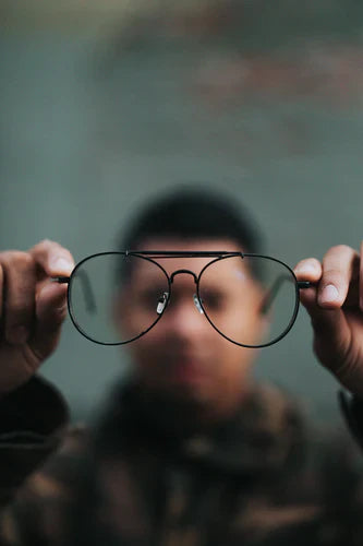 Wire-framed aviator glasses held up symbolizing effective vision setting to unlock school enrollment potential