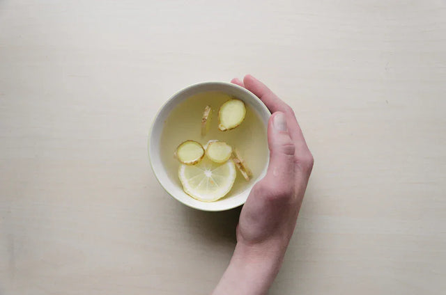 White ceramic cup with ginger tea and slices, symbolizing mental health awareness.