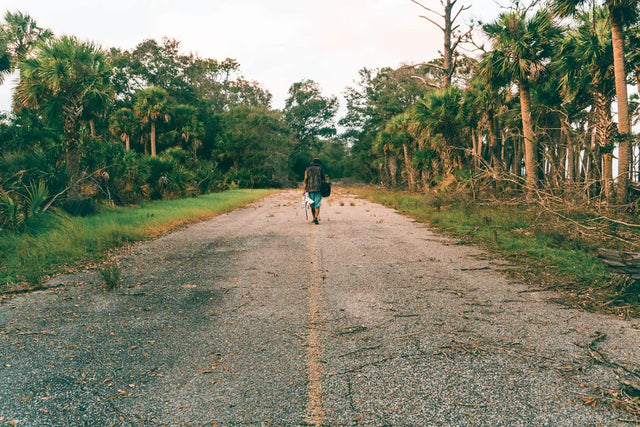Person walking on damaged asphalt road symbolizing embracing change and growth with Paisley High-Tops
