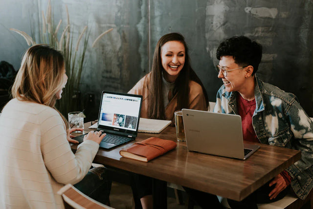 Three professionals discussing professional development around a wooden table in a collaborative school environment