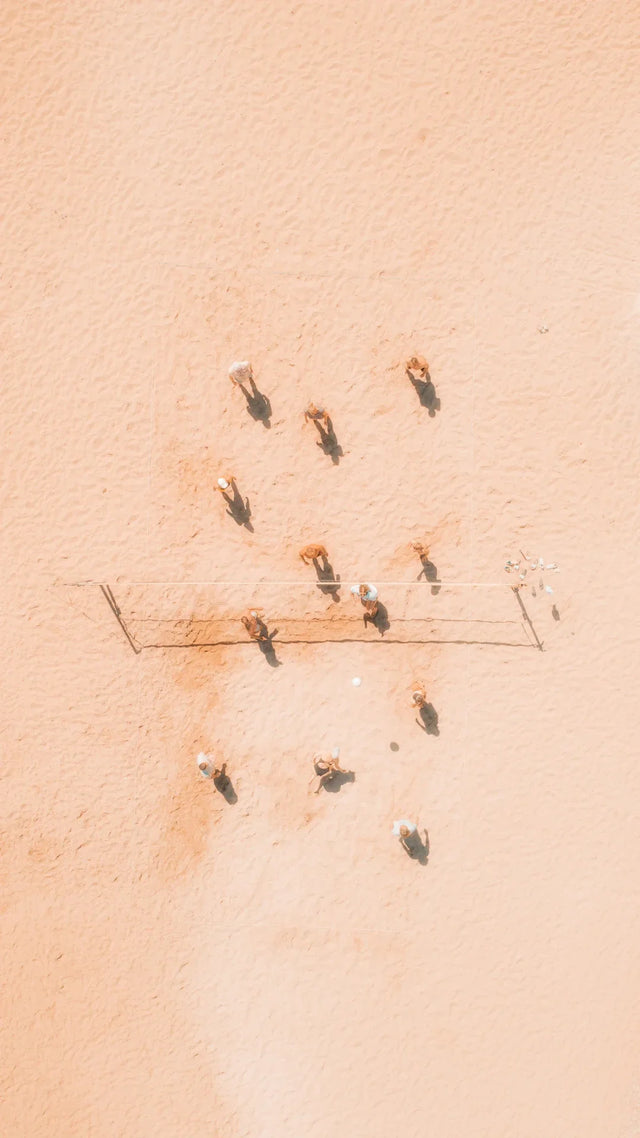 Overhead view of people playing soccer on sandy field emphasizing habit formation and daily routine