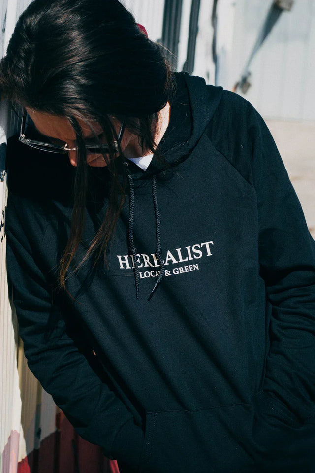 Black herbalist hoodie with white text and drawstrings, perfect for hustle culture.