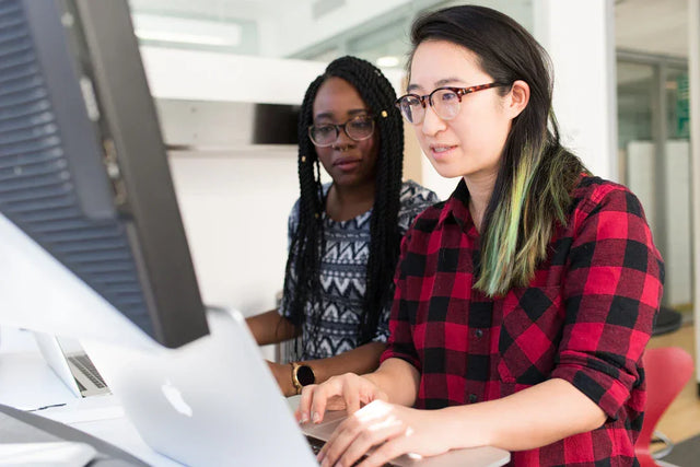 Two women collaborating on computers to develop an effective action plan for SMART goals