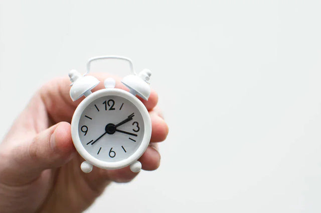 White miniature alarm clock symbolizing time management for avodah dynamics to prioritize tasks effectively