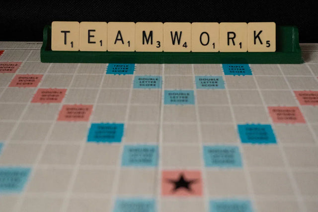 Scrabble tiles spelling out TEAMWORK on a game board rack for school leadership success