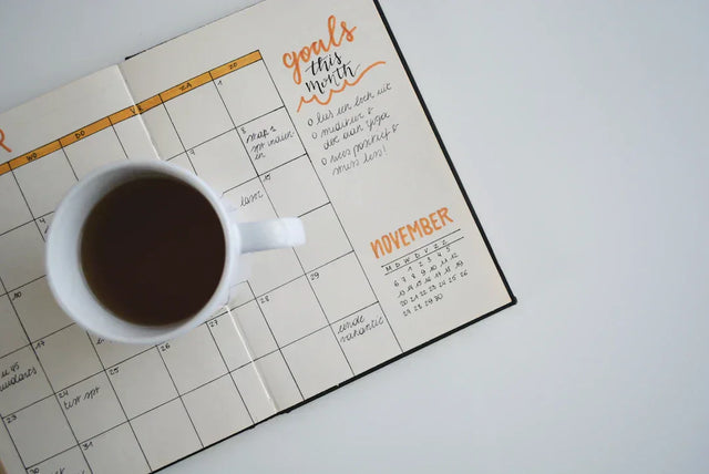 Open planner with a white mug of dark liquid symbolizing long-term and short-term goals