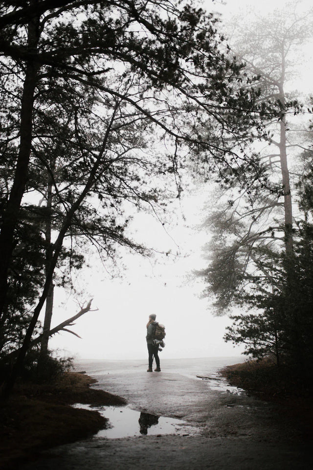 Person in work clothing with backpack on misty forest path reflecting hard work and achievement
