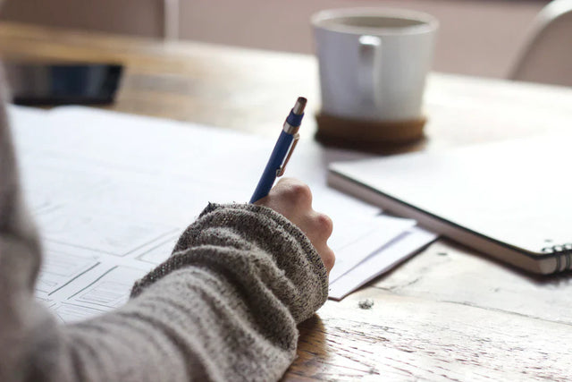 Hand holding a pen over paper reflecting remote work and leadership styles in teams.