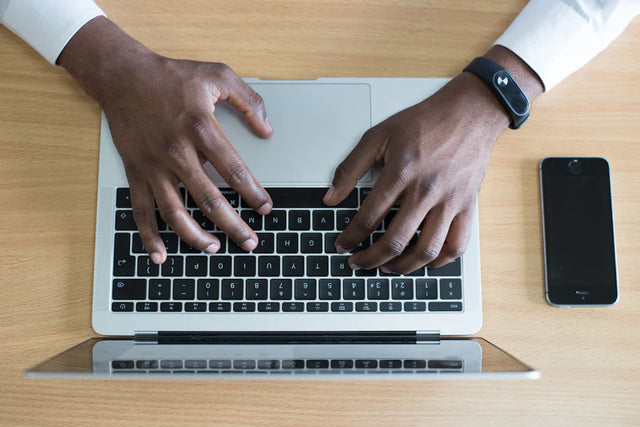 Hands typing on a laptop with smartphone nearby illustrating the transformative power of continuous professional development for emerging leaders