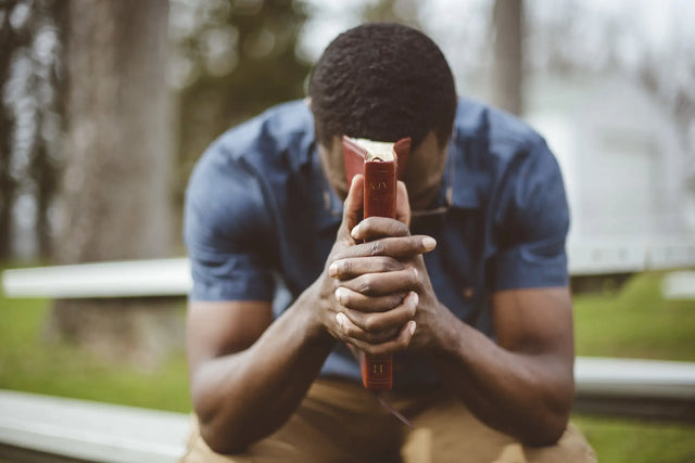 Man praying with a book, seeking supernatural breakthroughs and divine intervention.