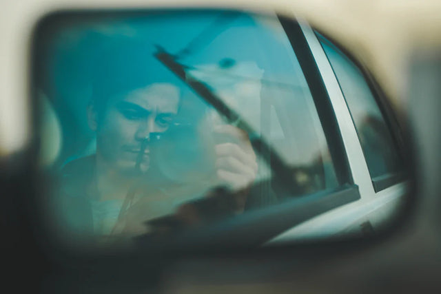Man’s face reflected in car’s rearview mirror illustrating online coaching and problem-solving skills