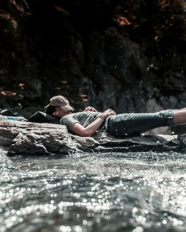 Man resting on a rock in water, highlighting the importance of sleep quality for work performance.