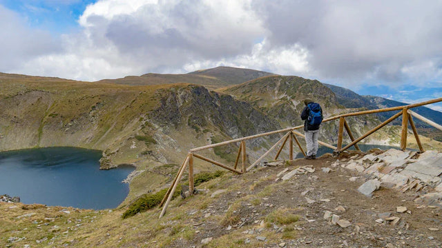 Hiker with blue backpack at mountain lake embodying core values and comfortable hustle