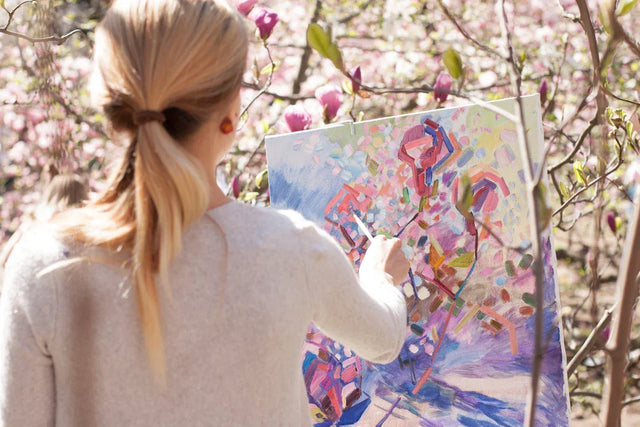 Woman with blonde hair in a ponytail painting abstract art to incorporate visualization techniques
