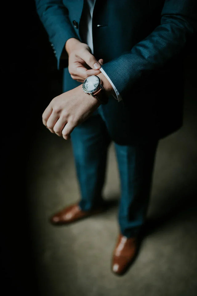 Person in teal suit adjusting watch, symbolizing actionable steps for business goals on a vision board