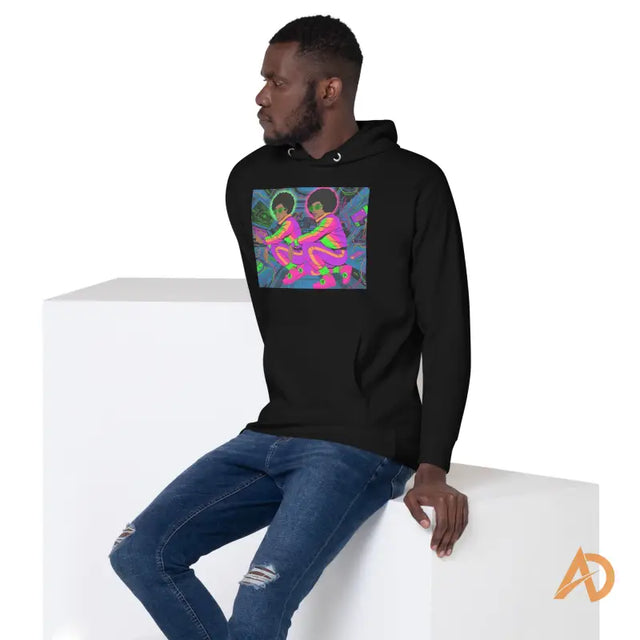 Galaxy Focus Hoodie by Avodah Dynamics: black with neon figuresYoung Black man in a black hoodie with roller skate graphic, sitting on a white block in a minimalistic studio.