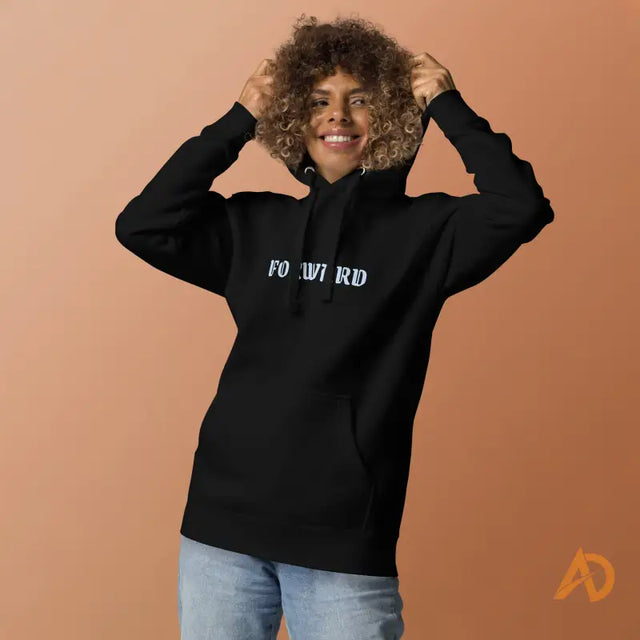 Black Galaxy Forward Hoodie with forward text designSmiling woman in black FO WIRD hoodie and jeans holding strings, peach background, orange A logo.