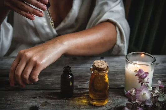 Glass bottles of essential oils and flower-adorned candle for overcoming burnout
