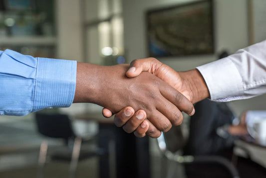 Handshake in blue and white button-down sleeve symbolizing strong partnerships through shared values
