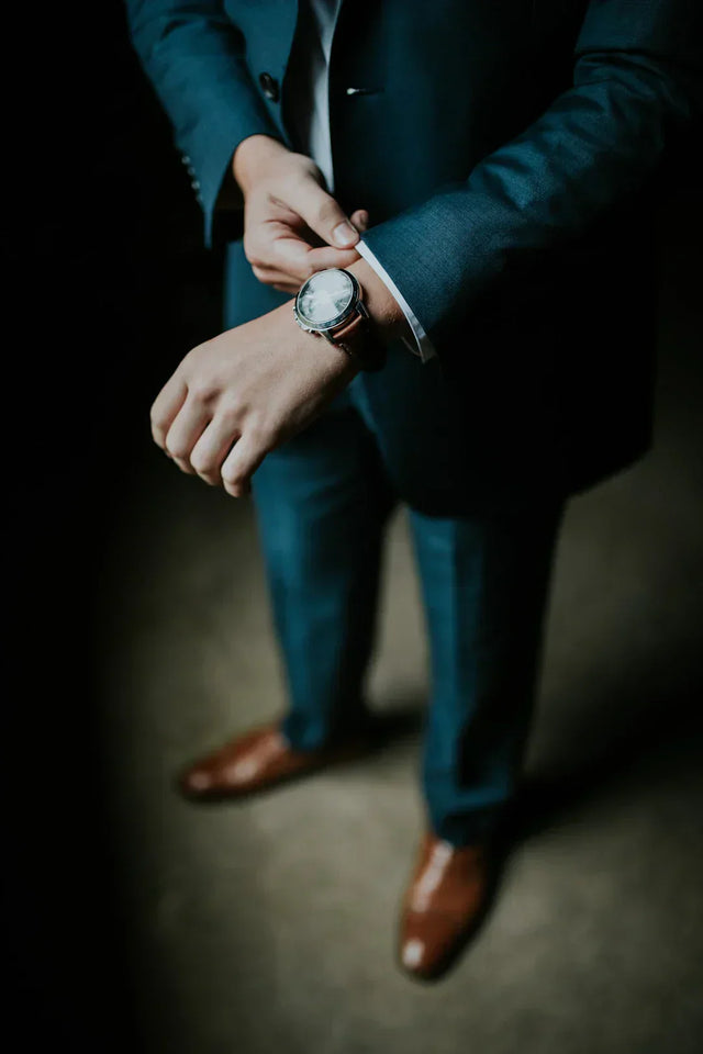 Professional in teal suit adjusts watch on vision board strategies image