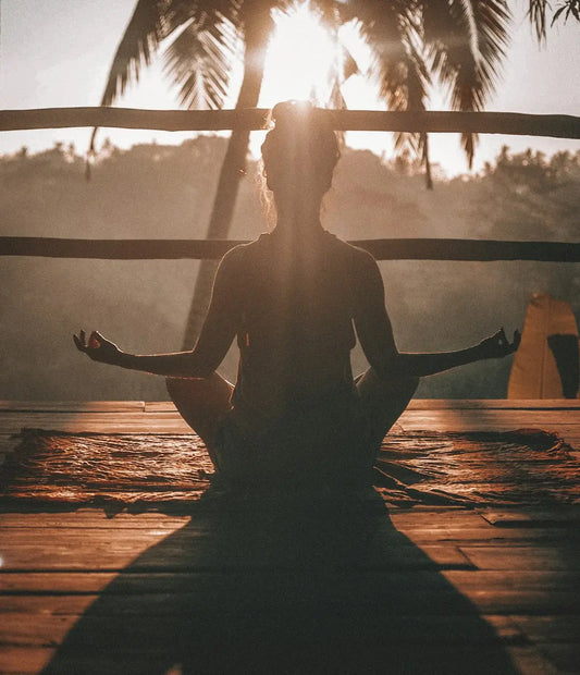 Silhouetted figure meditating at sunset, symbolizing cultivating positive habits for personal growth.