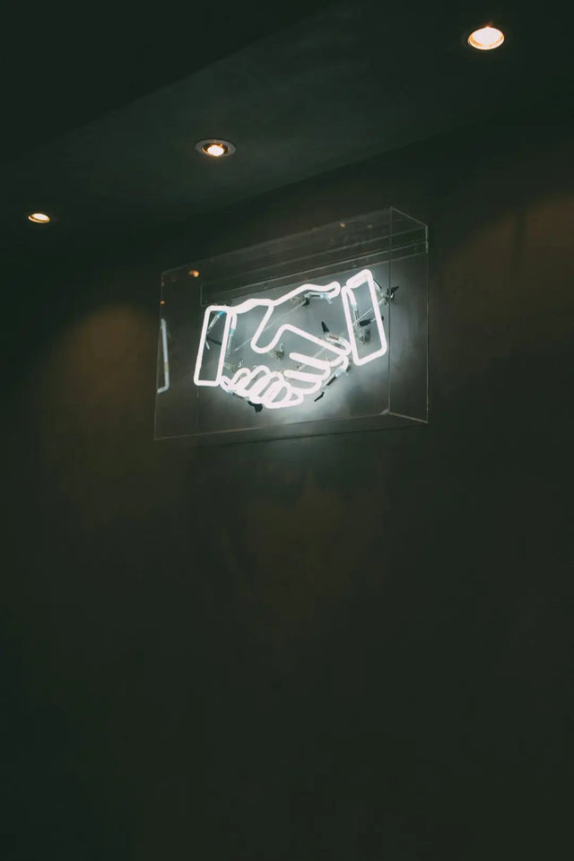 Neon light sign featuring a handshake symbol representing effective communication strategies.