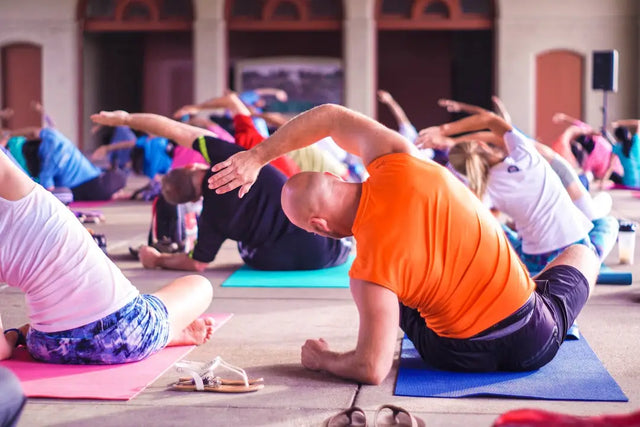 Group of individuals engaged in yoga practice on colorful mats promoting physical activity.