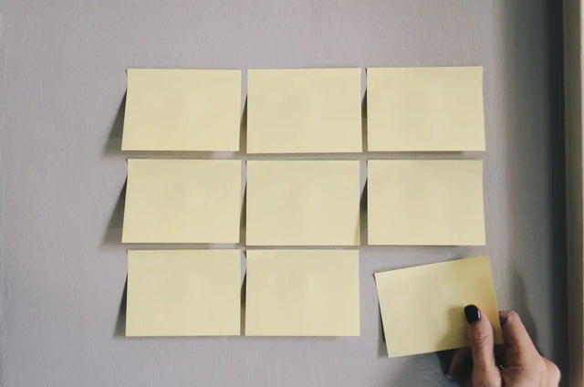 Yellow sticky notes in a grid symbolize daily routine for integrating work-life balance.