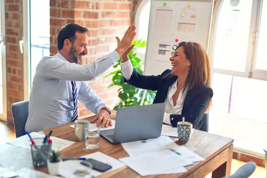 Two coworkers celebrating a high-five, showcasing effective communication in hustle culture.