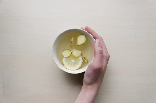 White ceramic cup with ginger tea and slices, symbolizing mental health awareness.