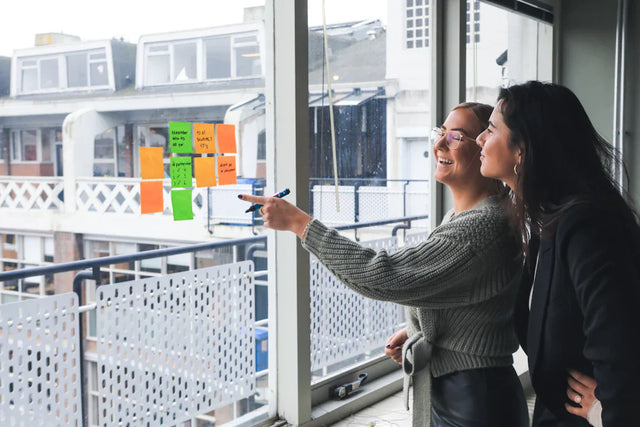 Two individuals examining colorful sticky notes for future-focused student success strategies.