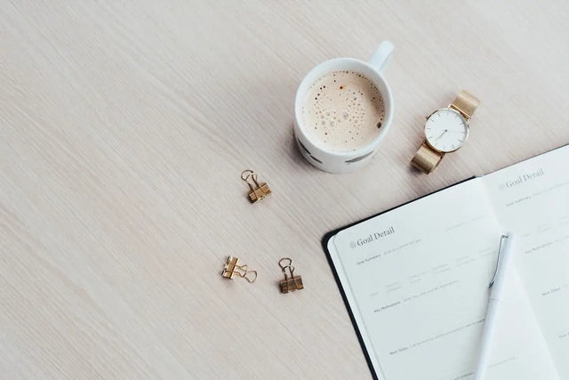 Creamy coffee and planner symbolizing daily routine for healthy habits in hustle culture.