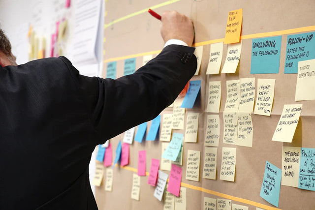 Colorful sticky notes on a wall highlighting empowering teacher leaders for enrollment growth.