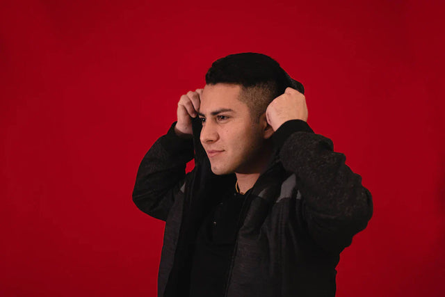 Young man with modern haircut wearing dark hooded jacket exemplifying growth mindset and receiving feedback