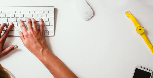 Hands typing on a white wireless keyboard, embracing technological disruption through data analytics.