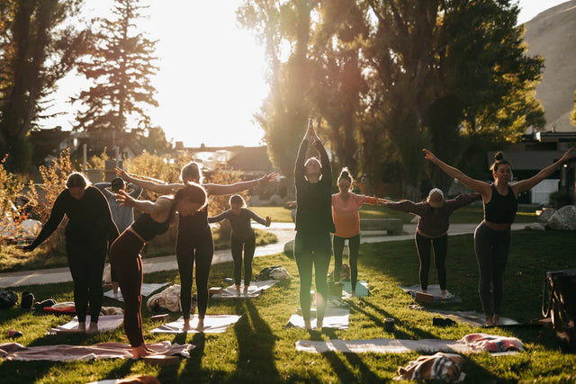 Women practicing yoga outdoors to promote healthy habits and enhance time management for business success