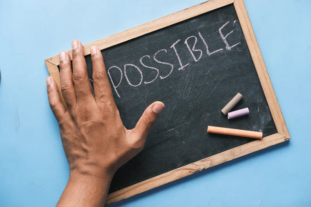 Hand covering IM on blackboard with POSSIBLE written, illustrating recognizing opportunities for growth