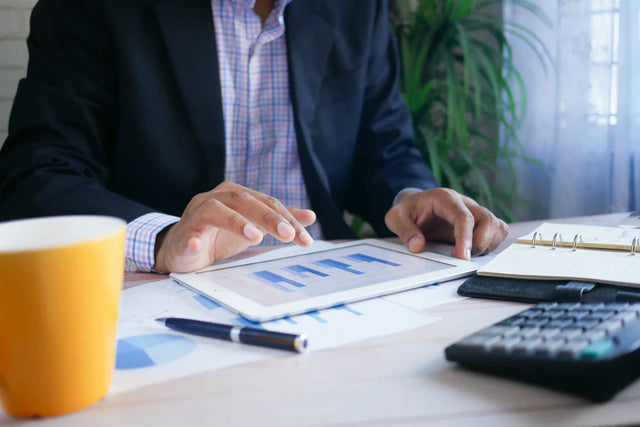 Hands interacting with a tablet displaying bar graphs for business level and personal development strategies