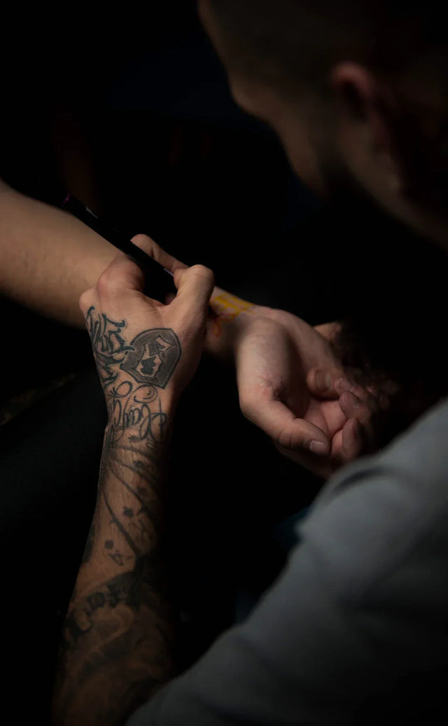 Tattooed arm being marked for smart goals in hustle culture celebration of milestones
