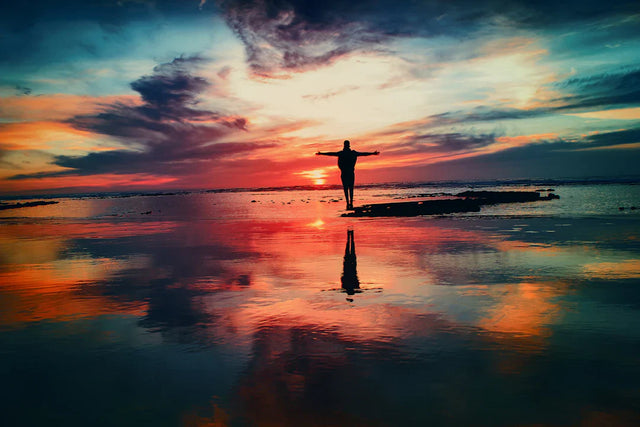 Person with arms outstretched on reflective water at sunset symbolizing success mindset and growth