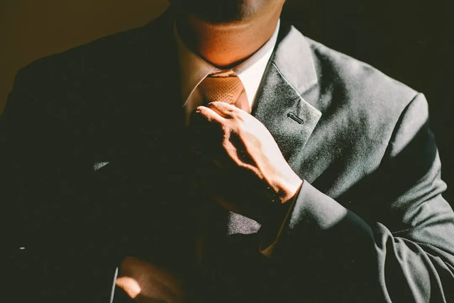 Gray suit jacket with a hand adjusting the tie, symbolizing key communication skills.