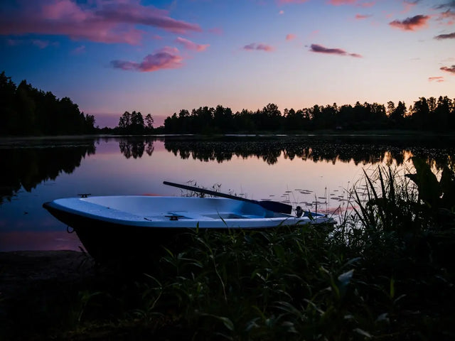 A boat rests along the shoreline at dusk, symbolizing resilience amid hustle culture.